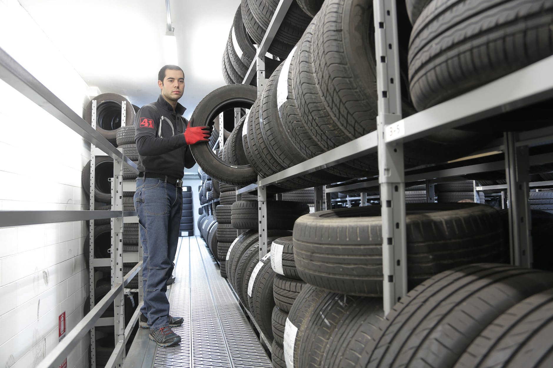 man in black jacket standing beside black tires
